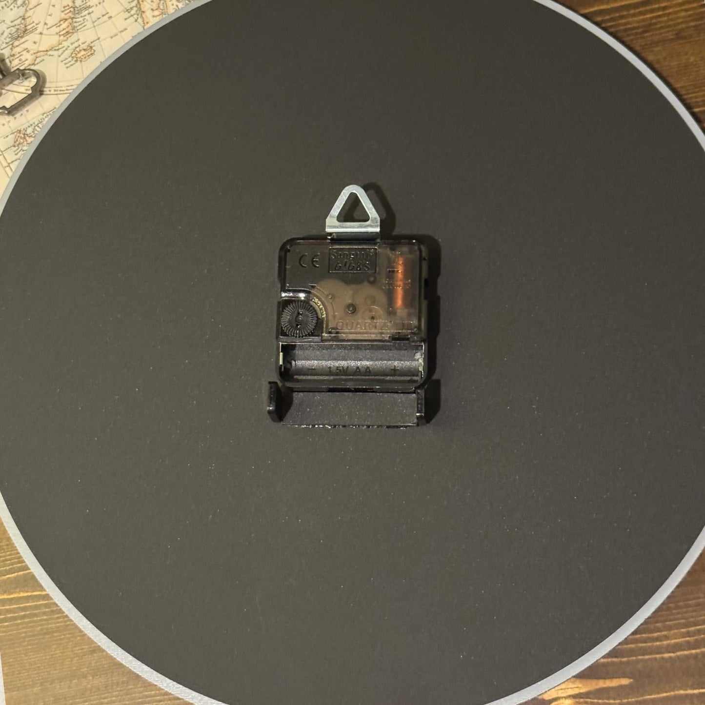 Clock mechanical component on a dark round surface with a wooden background