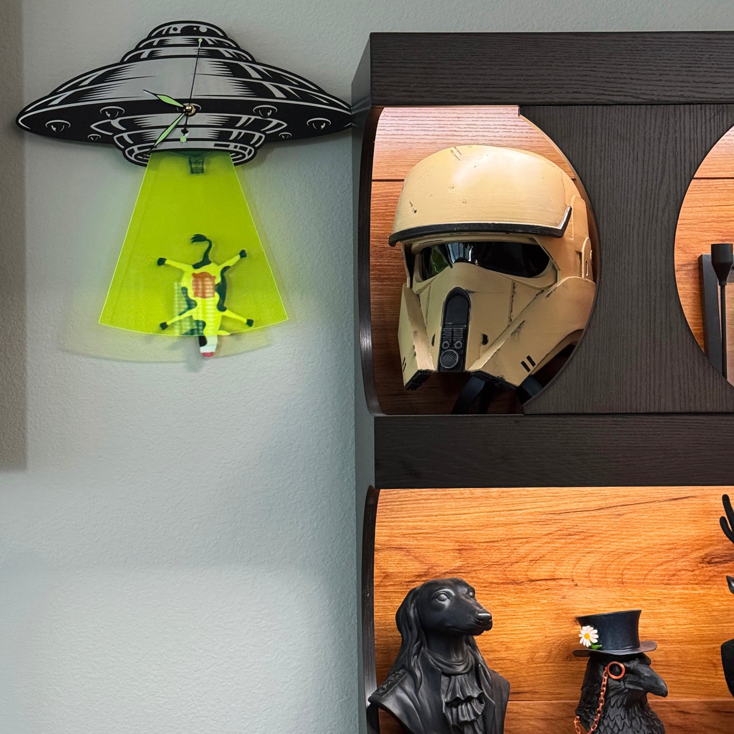 Decorative wall shelf with a helmet, UFO model, and other items on a gray wall.