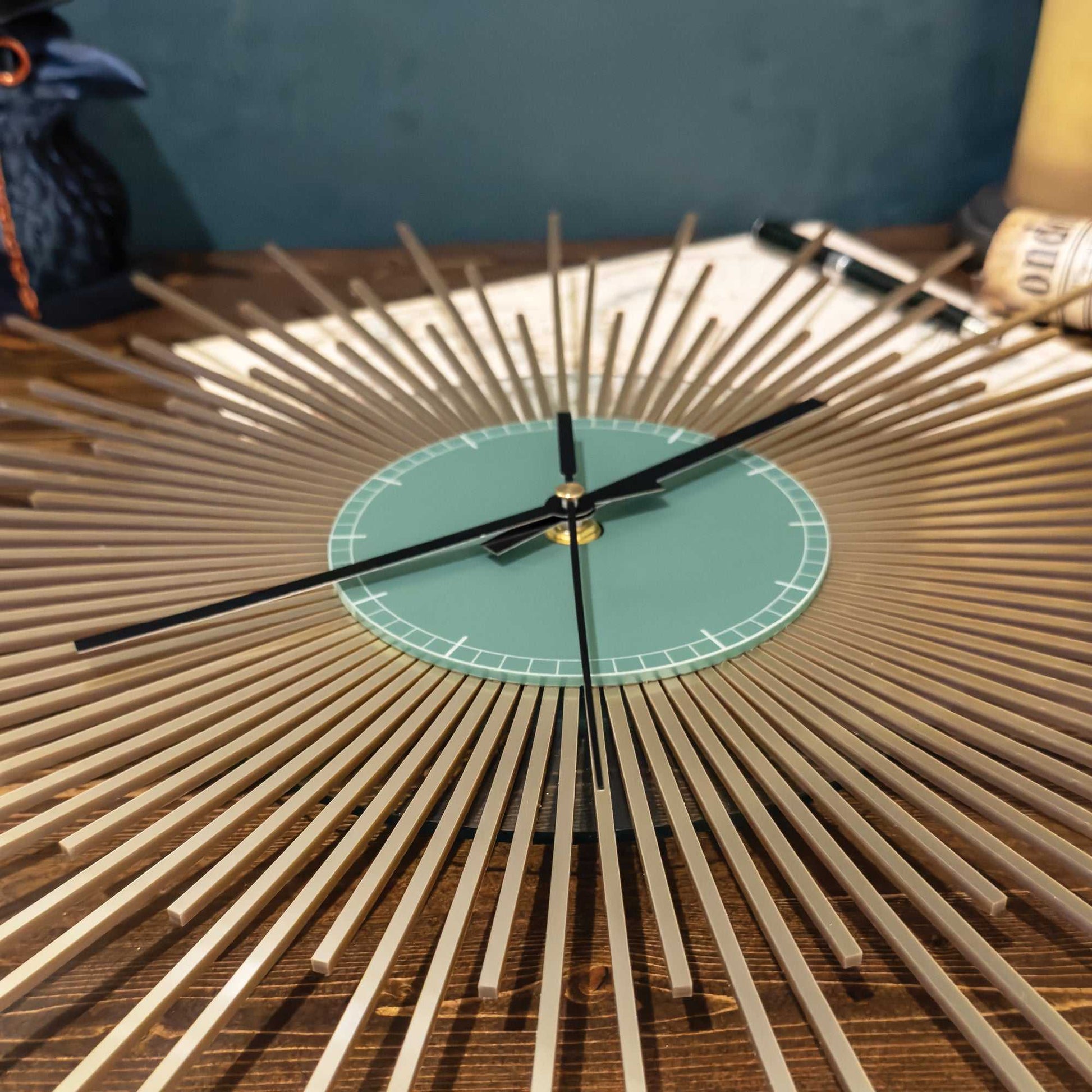 Gold wall clock with a green face on a wooden surface.