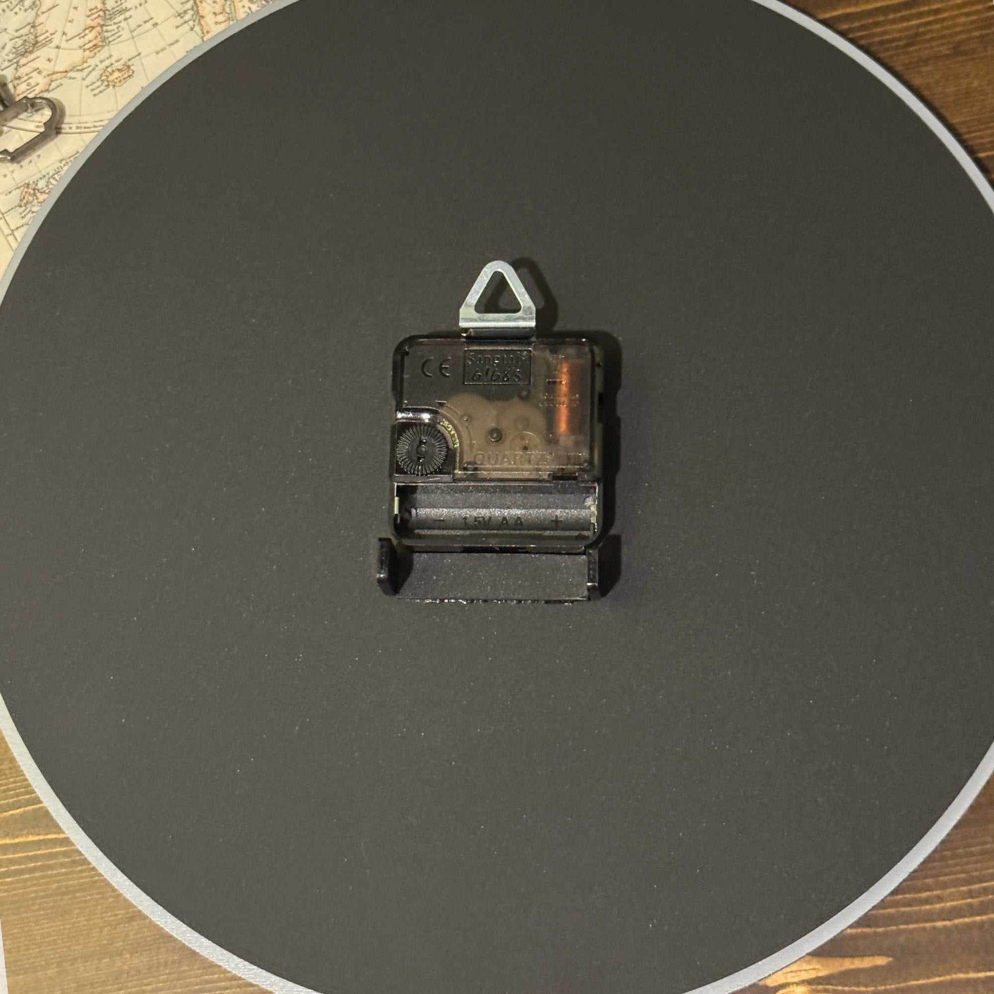 Clock mechanical component on a dark round surface with a wooden background